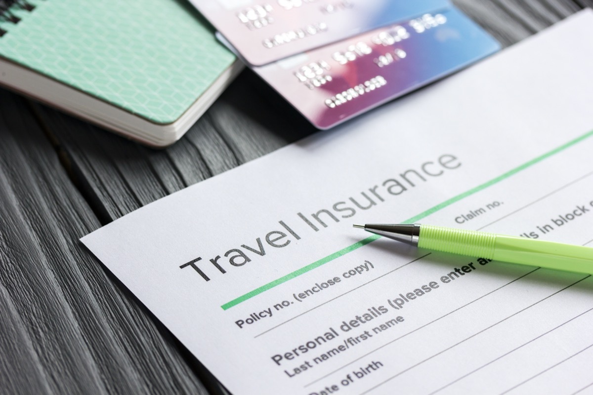 Travel preparation concept with insurance and cards on wooden table