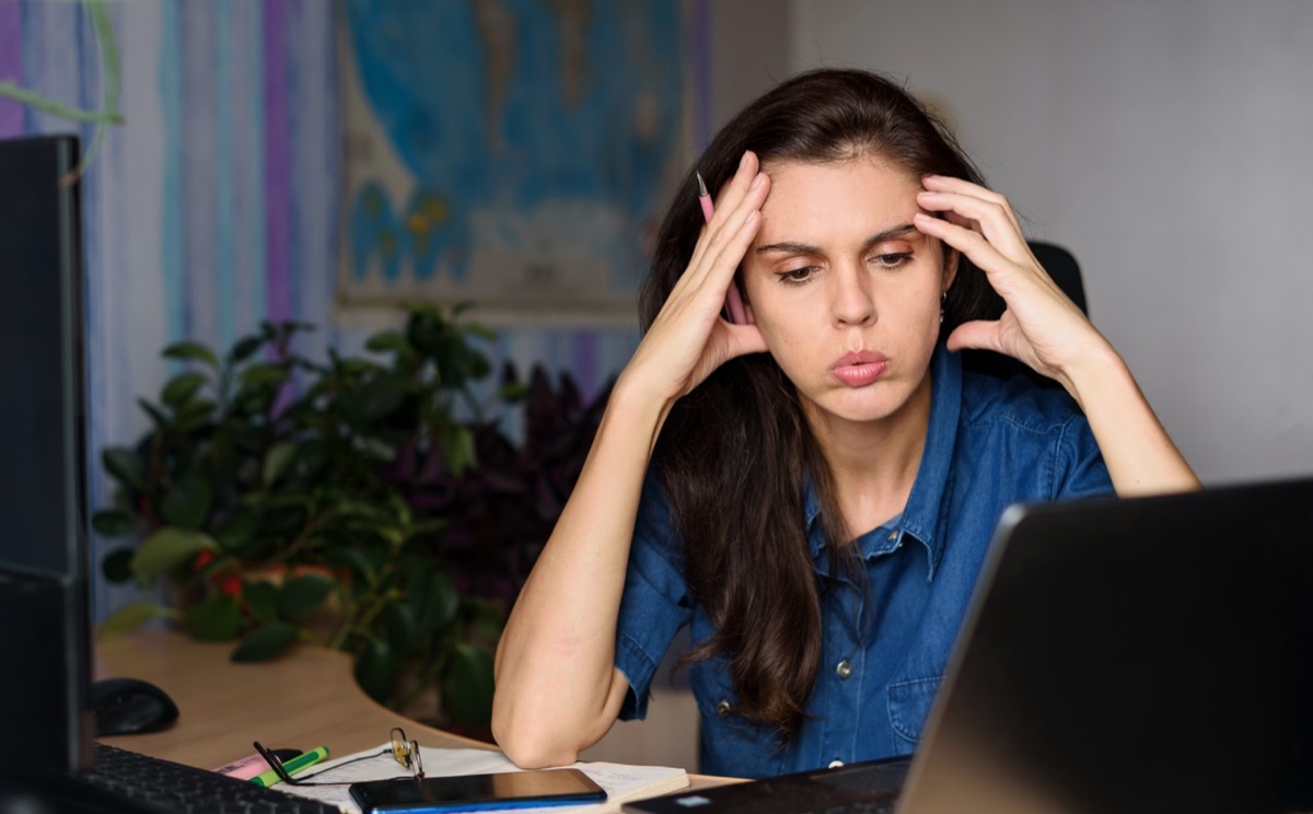 stressed woman sitting at her desk in front of computer working hard