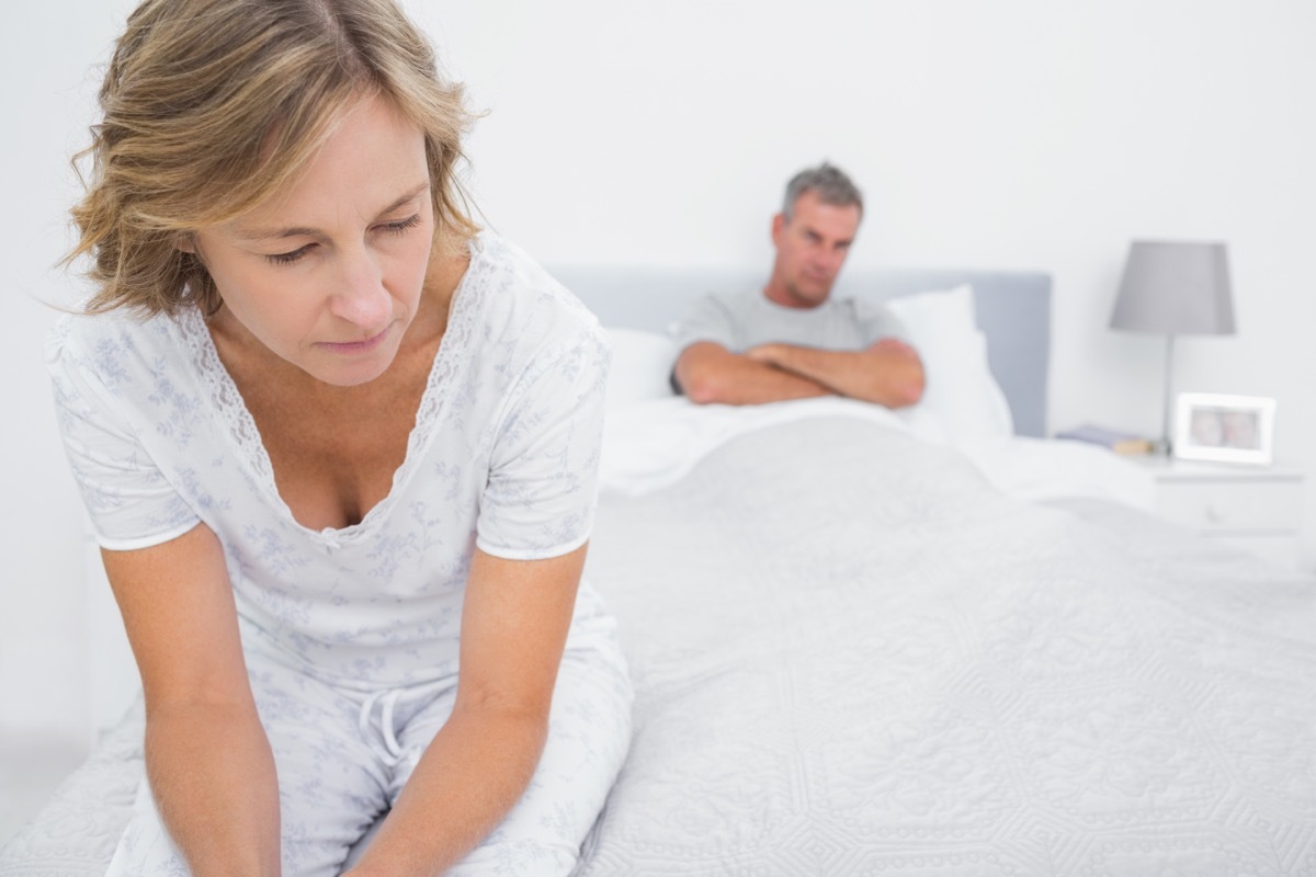 Couple sitting on opposite ends of bed