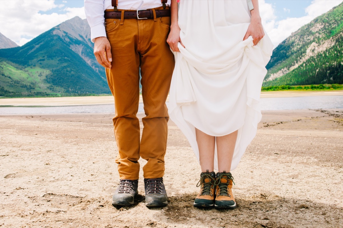 Close up from the waist down of groom and bride in hiking shoes 