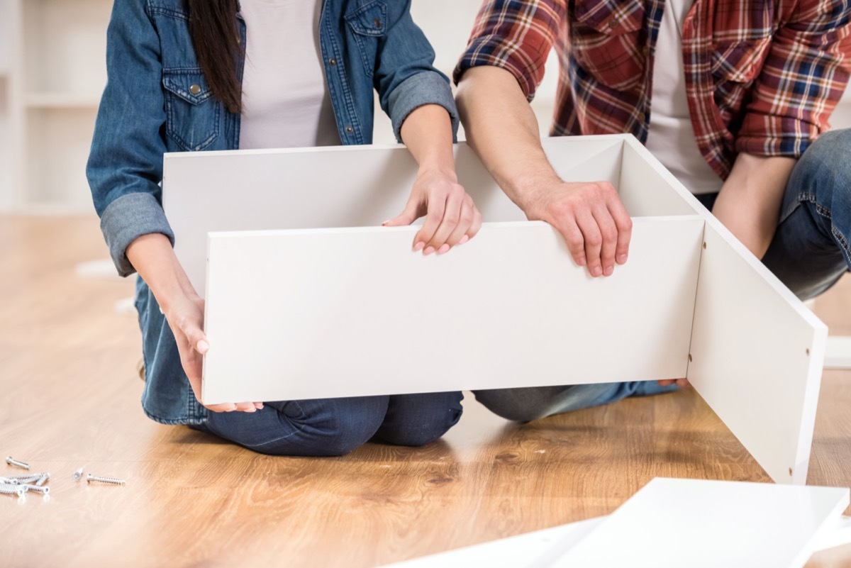 couple putting together white cabinet