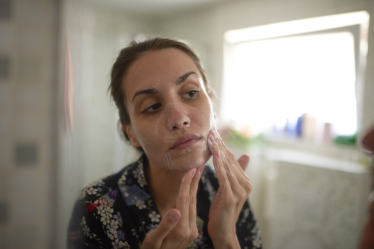 Woman looking at her skin in a mirror.