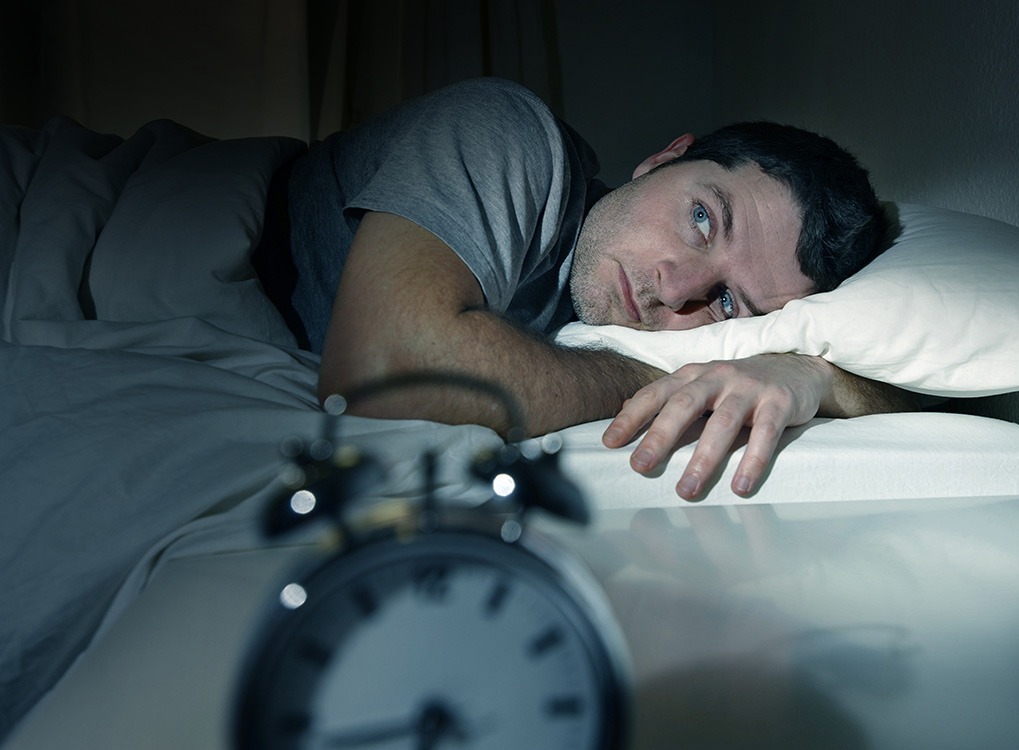 man in bed looking at alarm clock, ways your body changes after 40