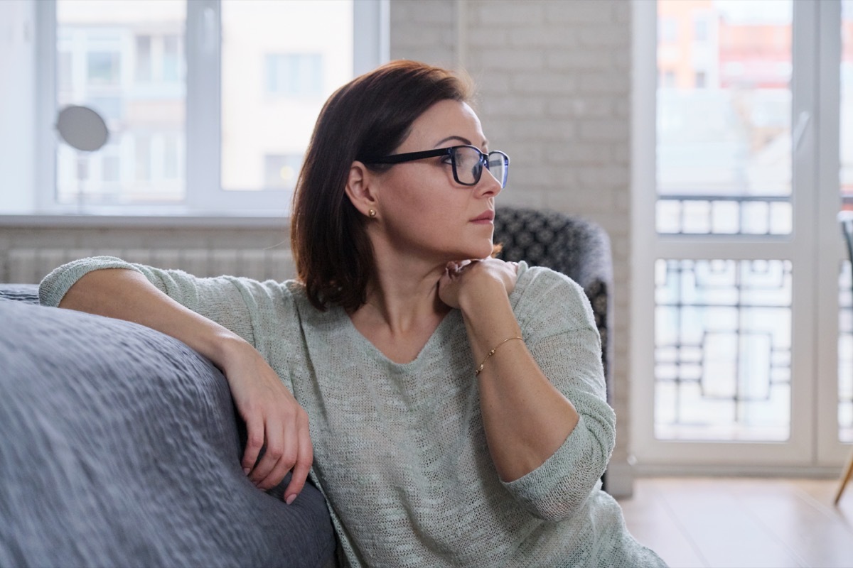 mature woman sitting on the floor at home, sad middle-aged woman alone experiencing health problems and personal troubles