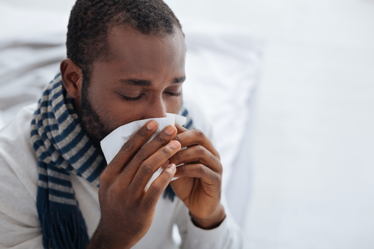 Ill person blowing his nose with closed eyes