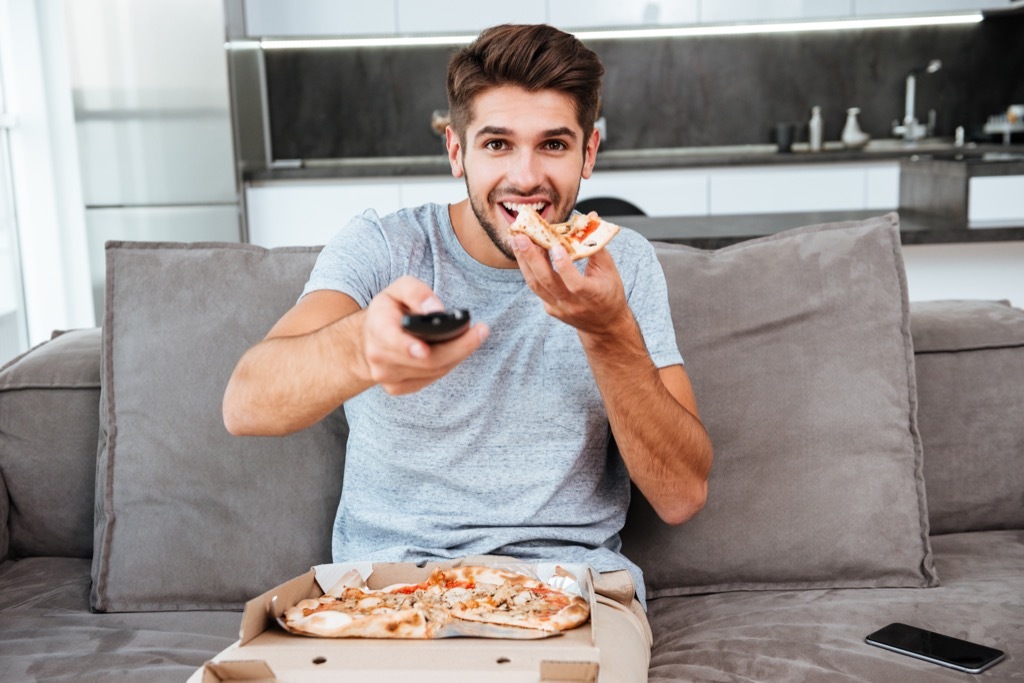 man eating food in front of the television