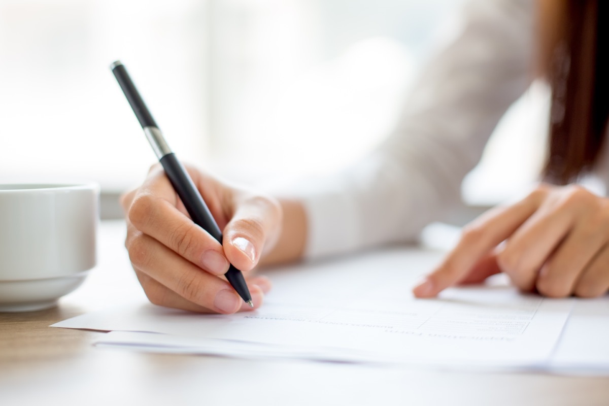 young woman signing contract with black pen