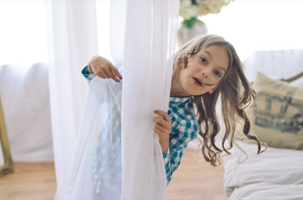 little girl behind curtain