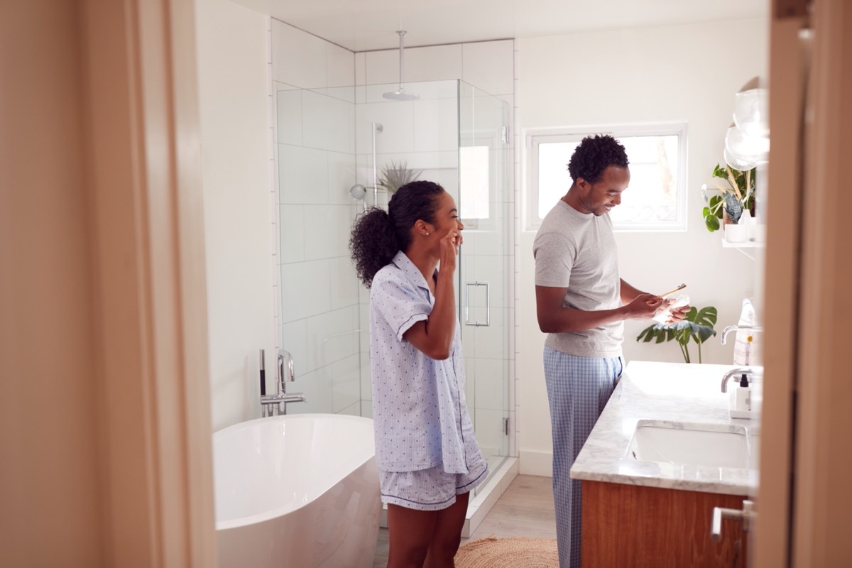 couple brushing their teeth in bathroom