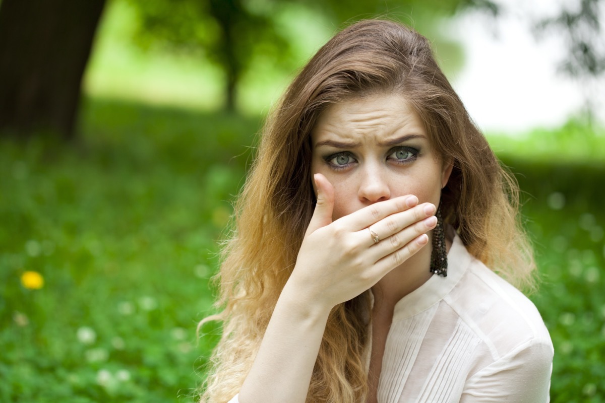 covers her mouth with his hand, posing outdoors in summer park