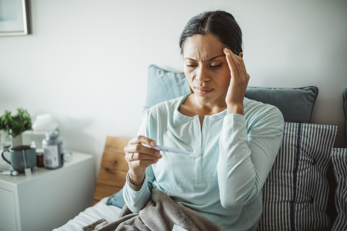 Woman uses thermometer to measure temperature