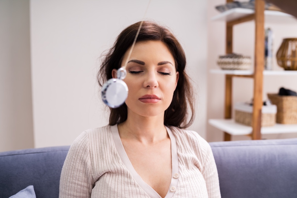 Woman being hypnotized by using pendulum.