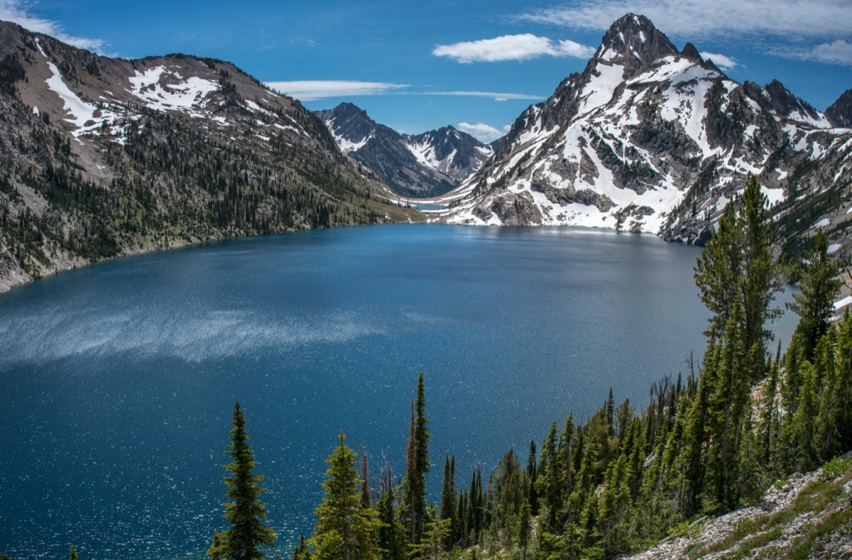 Sawtooth Lake in Idaho wilderness framed with pine trees and rugged snow capped mountain peaks