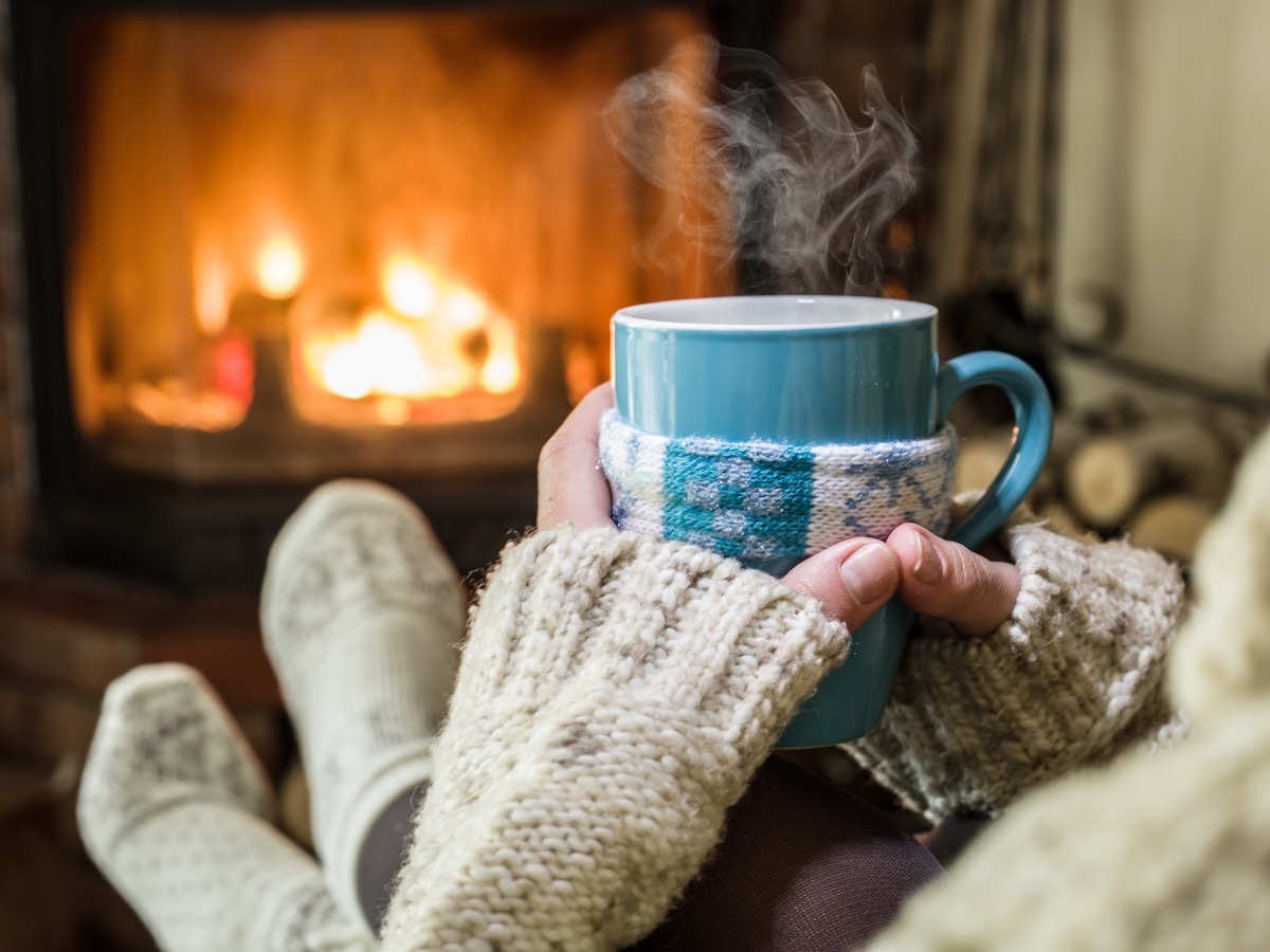 Woman drinking tea by the fireplace