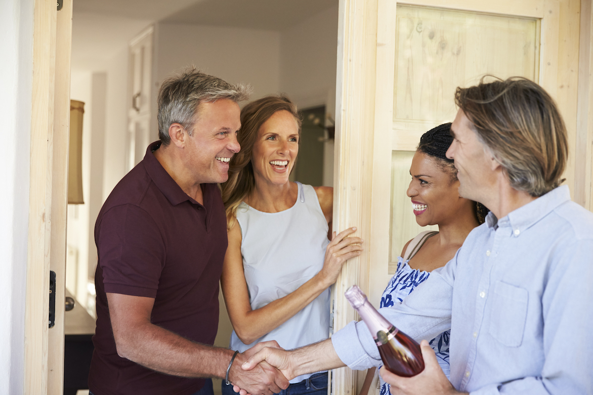 Couple greeting their guests at the door of their home