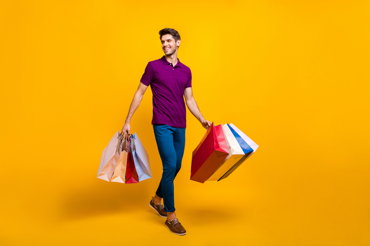 Full length body size view of his he nice attractive cheerful cheery glad content guy carrying new things colorful packages isolated over bright vivid shine vibrant yellow color background