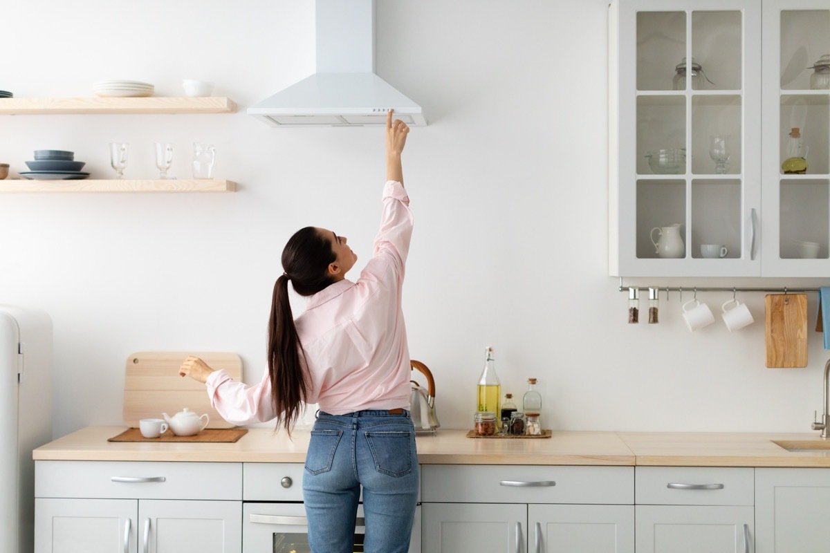 woman turning on exhaust hood