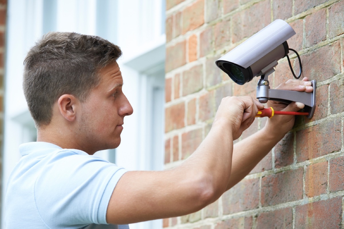 man installing security camera, bad home renovations