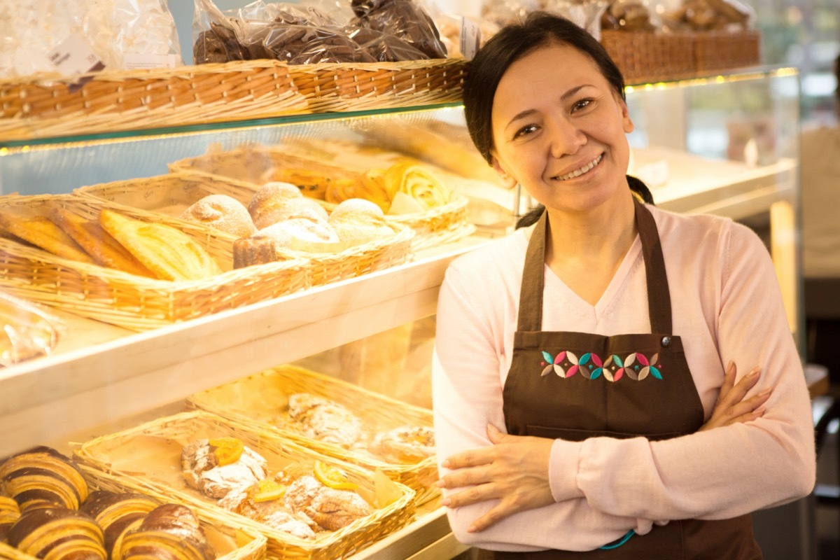 middle age asian woman standing in front of her pastries