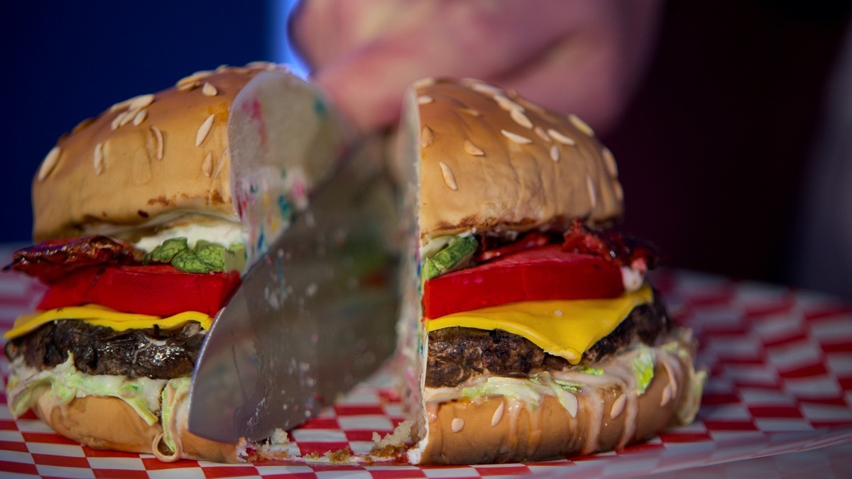 A burger-shaped cake being cut into on Is It Cake?