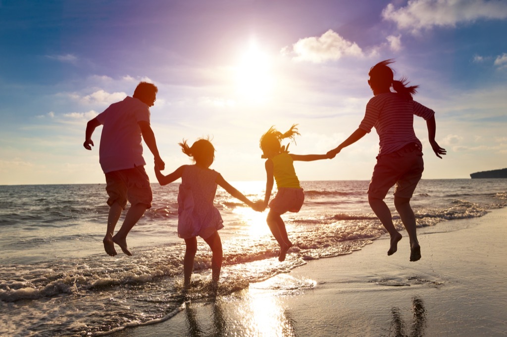 Shadowy photo of family of four jumping in ocean, summer facts