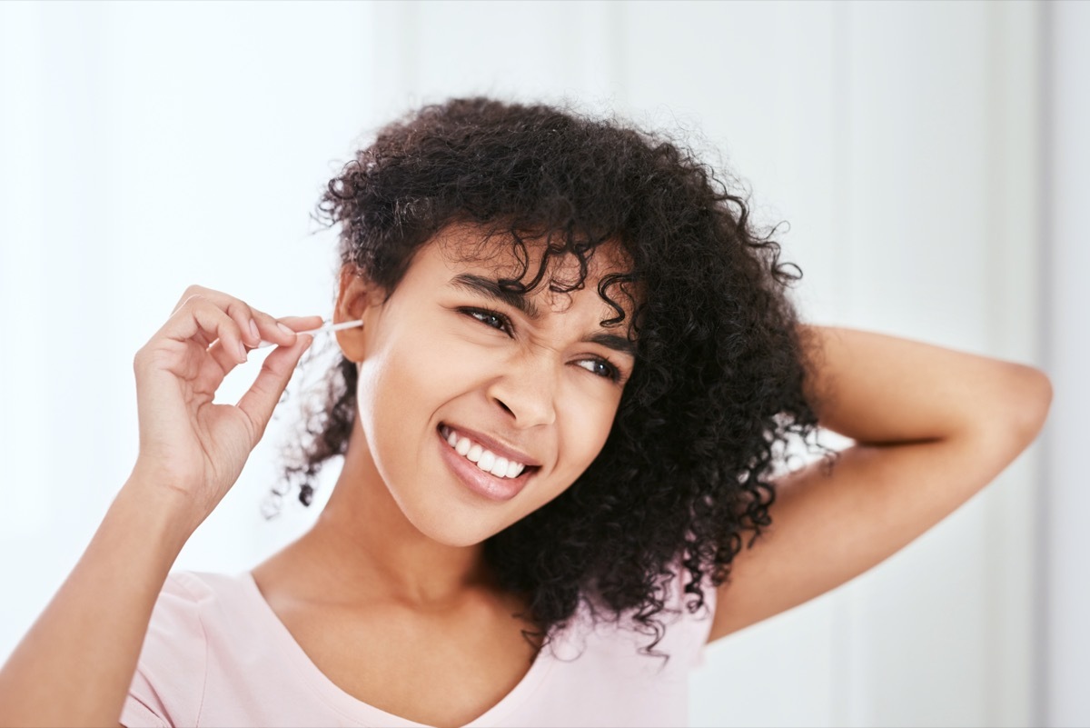 Cropped shot of an attractive young woman cleaning her ear with an earbud in her bathroom at home