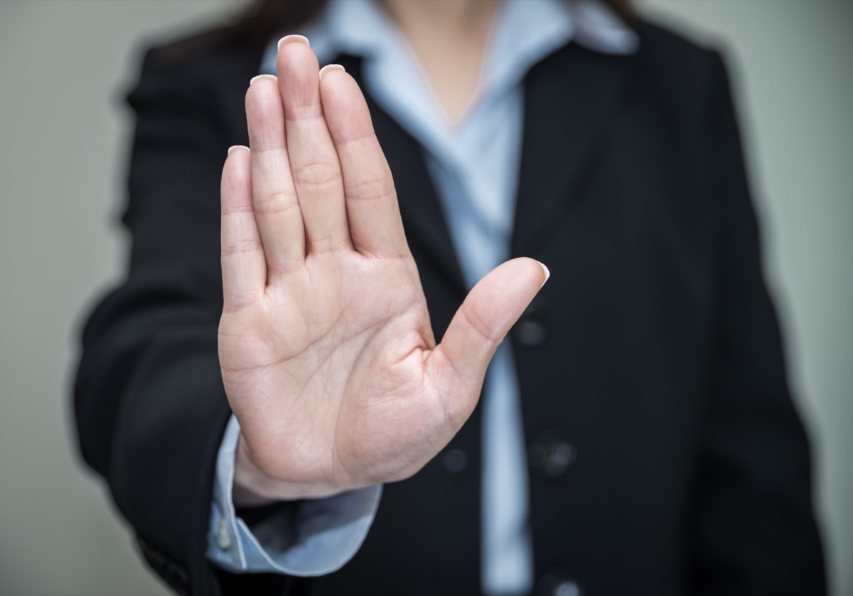 Woman in business suit showing her palm in grey background