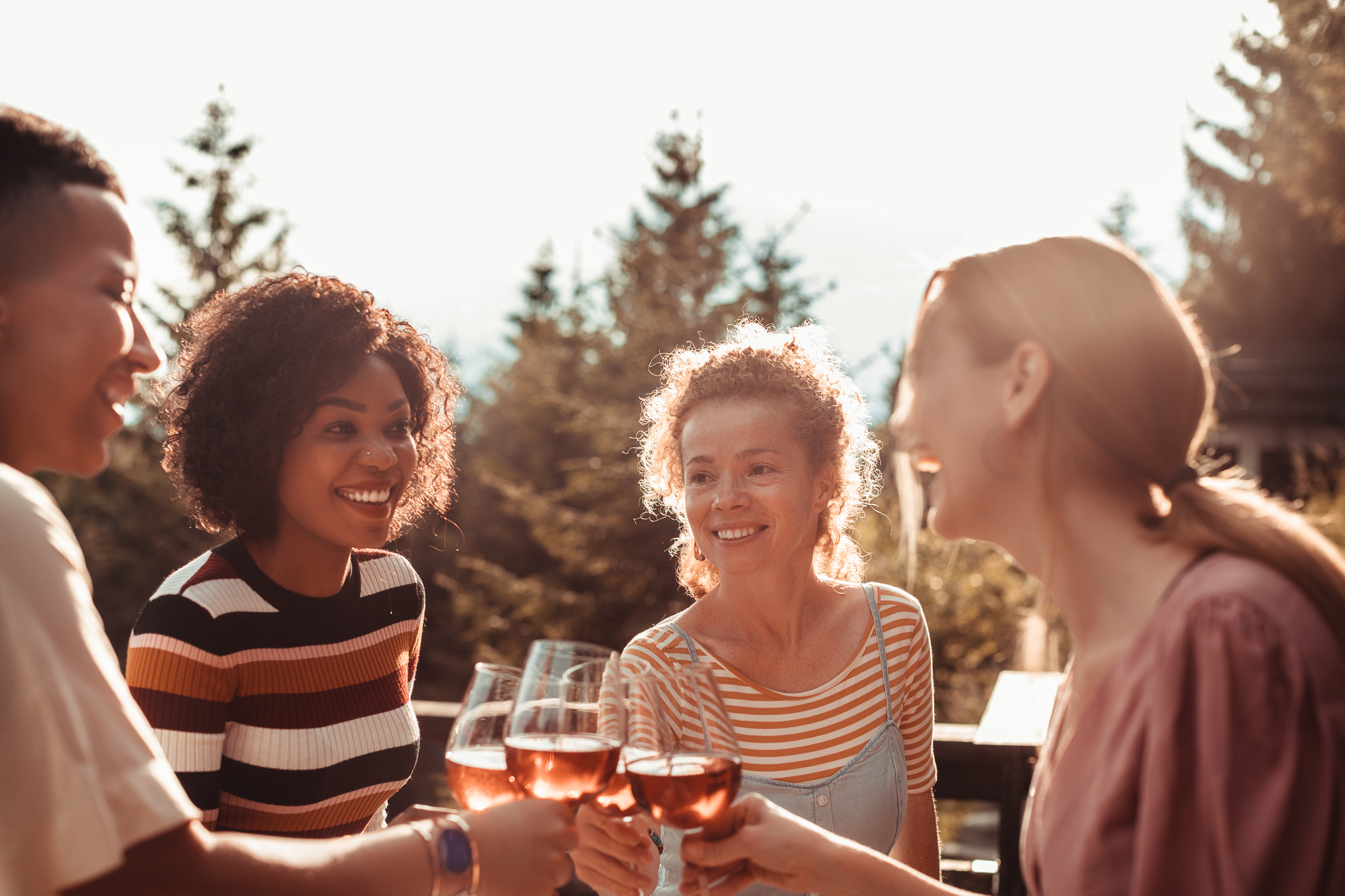 Close up of a group of friends enjoying wine after a dinner on the patio in the woods