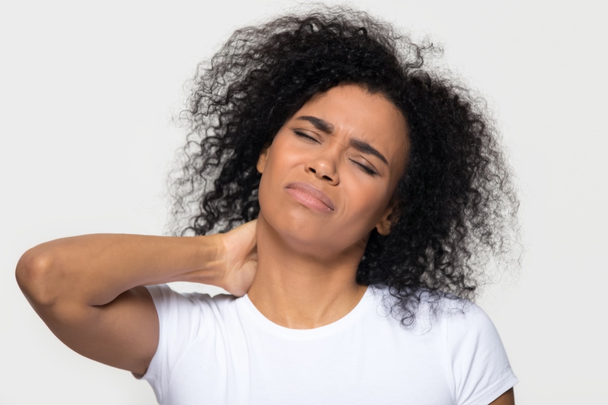 Tired upset african young woman massaging hurt stiff neck