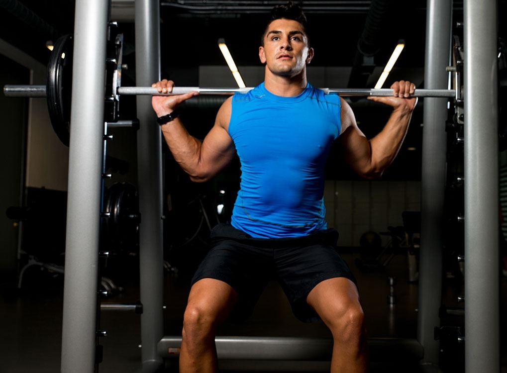 man lifting weights with a weight rack