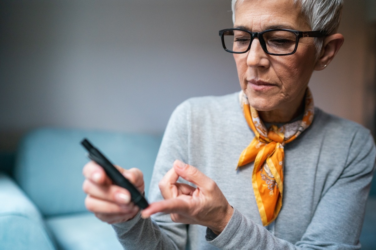 Modern Senior woman doing Diabetes blood test at home