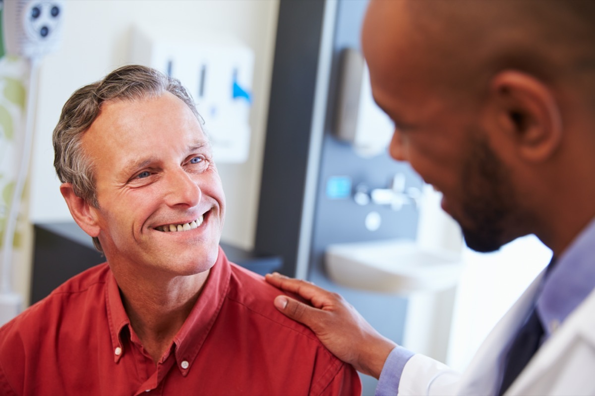 Male Patient Being Reassured By Doctor In Hospital Room