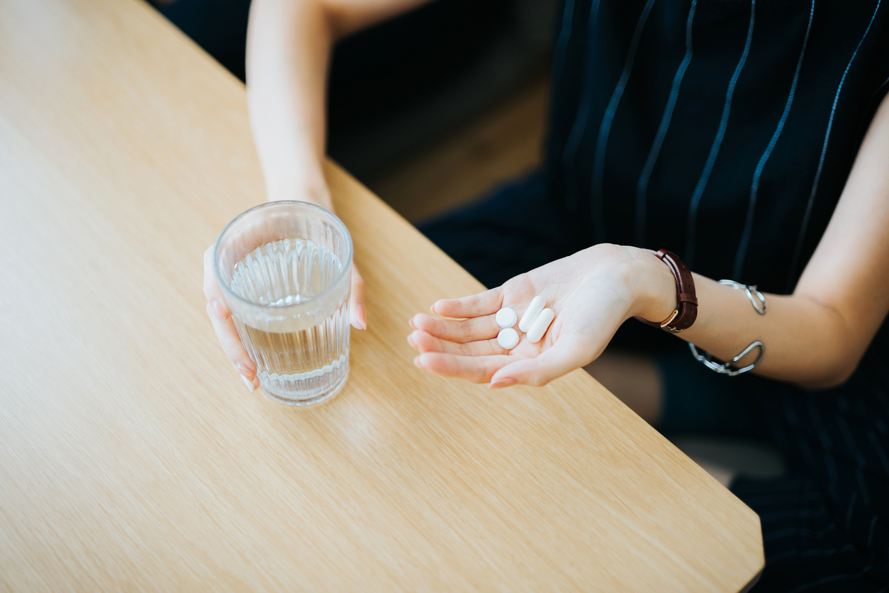 Close up of woman holding a glass of water and medication in her hand