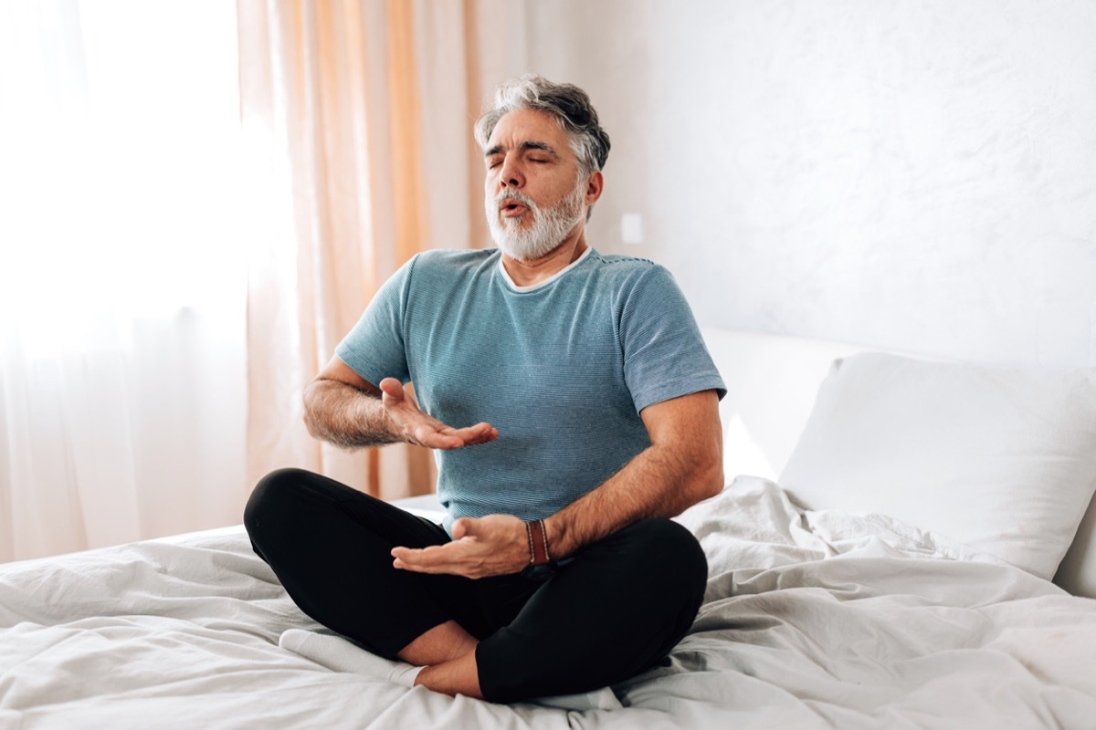 man practicing deep breathing in bed