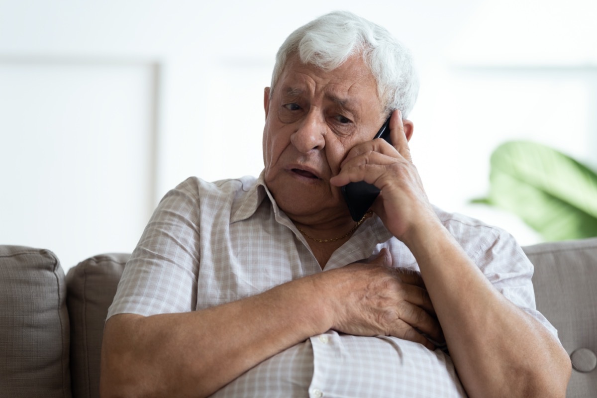 Upset older man touching chest, calling emergency, talking on phone, unhappy mature male having heart attack