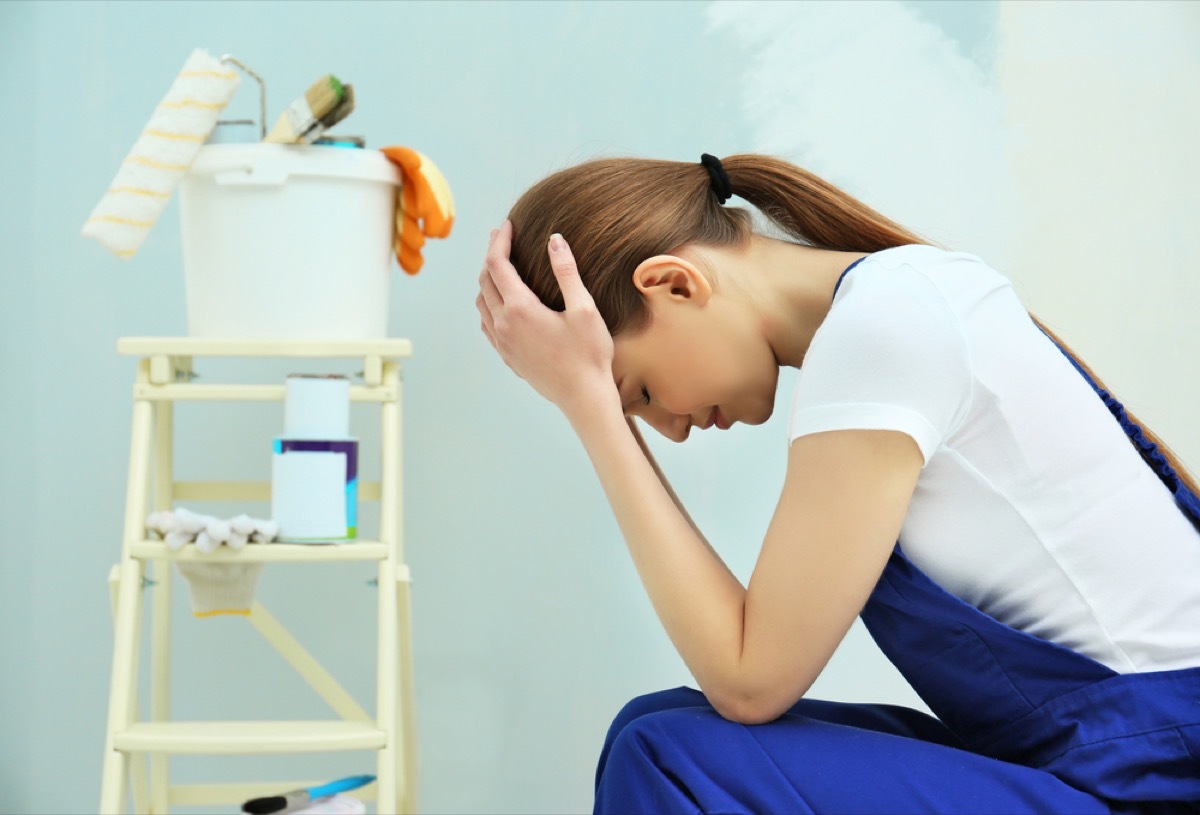 woman stressed during home reno project, hangs head in hands