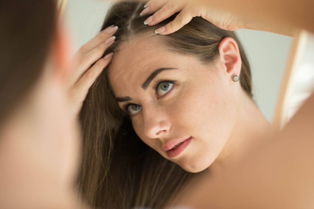 Woman touches her hair in front of the mirror