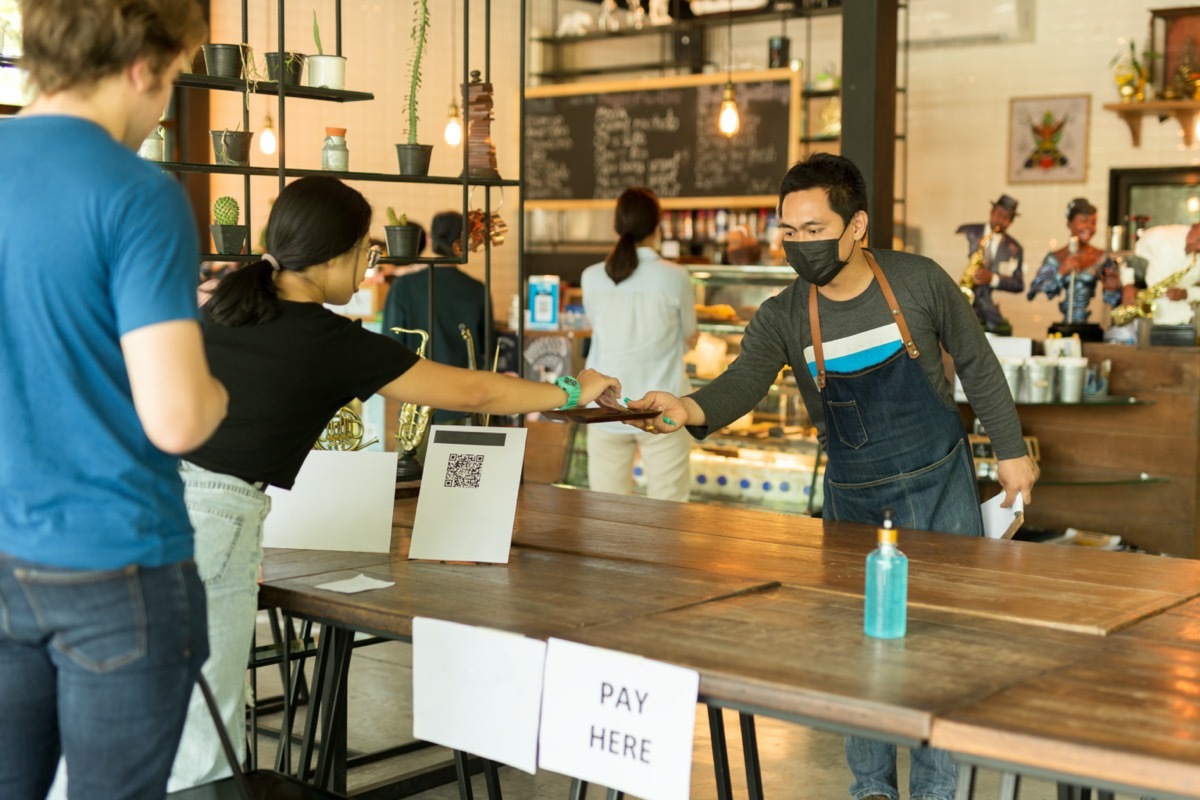 Social distance conceptual small business waiter serving customer in cafe.