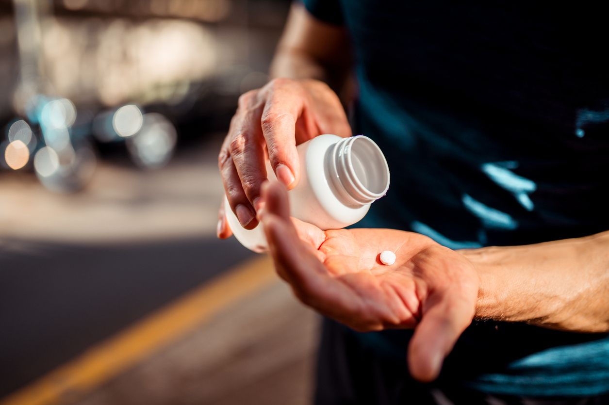 Hands pouring tablets from a bottle.